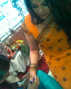 Woman in sari with henna being applied to hand