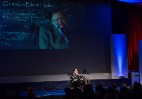 Professor Stephen Hawking sits on the Imperial Great Hall stage