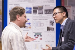 Two researchers discuss their results, with their research poster in the background