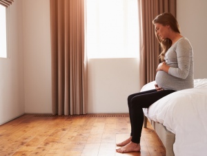 Heavily pregnant woman sitting alone and feeling sick