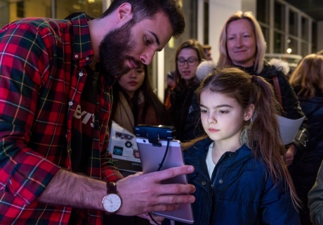 A researcher uses a tablet computer to scan the face of a young girl