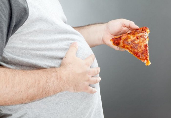 Obese person eating pizza