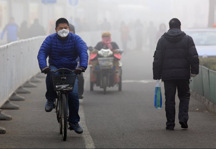 Man riding a bike with a mask on in smog