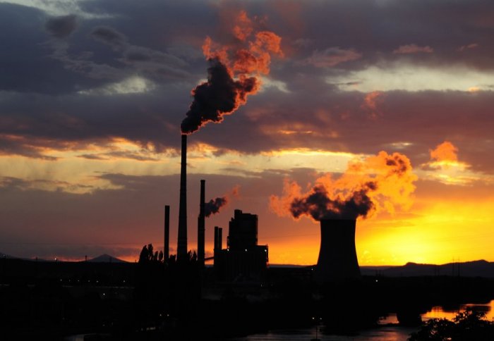 Coal power station with smoking chimneys in sunset