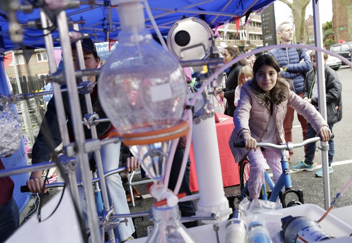 Girl on a stationary bike connected to a chemical flask