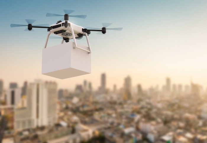 Rendering of a drone delivering a package over a cityscape