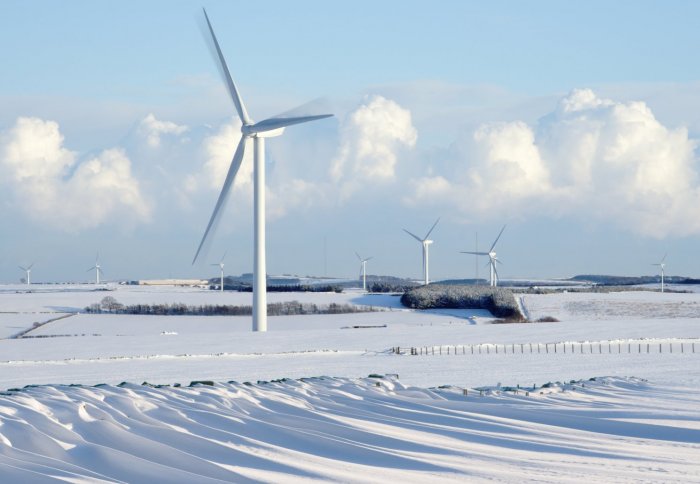 Wind turbines by a farm in the snow