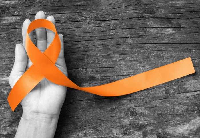 A hand holding an orange ribbon - the symbol of multiple sclerosis awareness