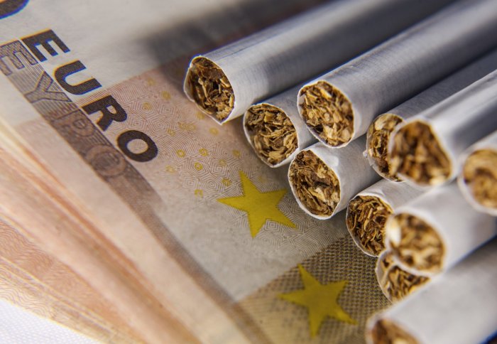 Three cigarettes on top of a pile of Euro coins and notes.