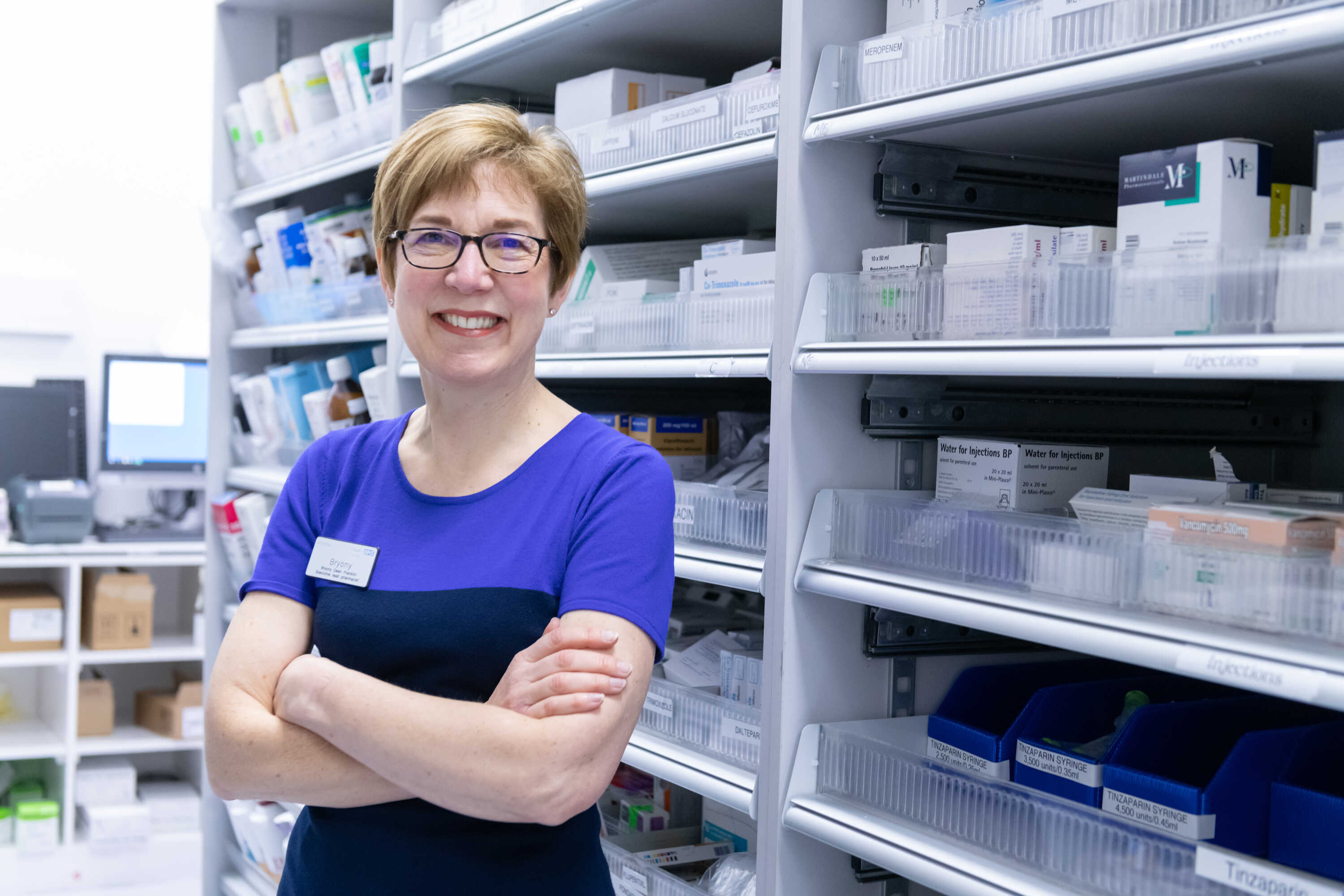 Professor Bryony Dean Franklin in a pharmacy with arms folded