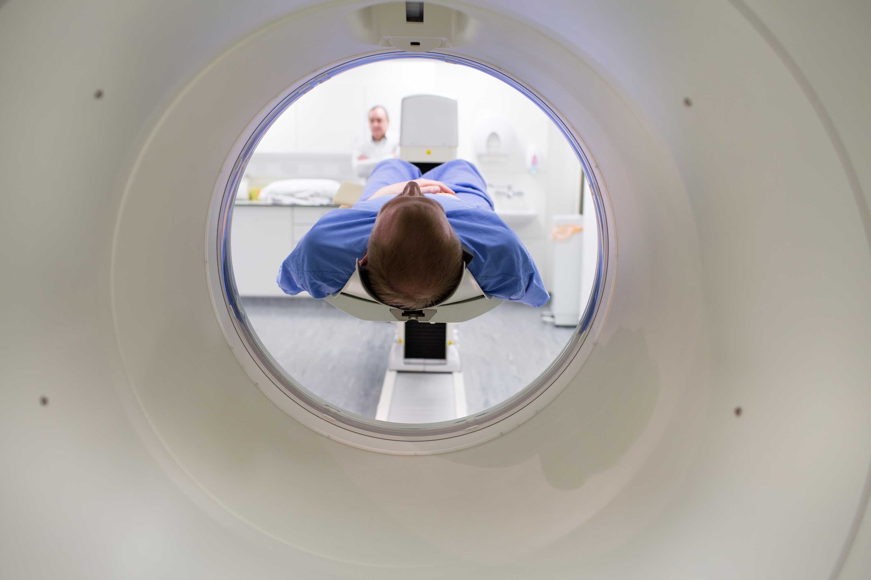a person (white, male in his 30s) undergoing PET scan