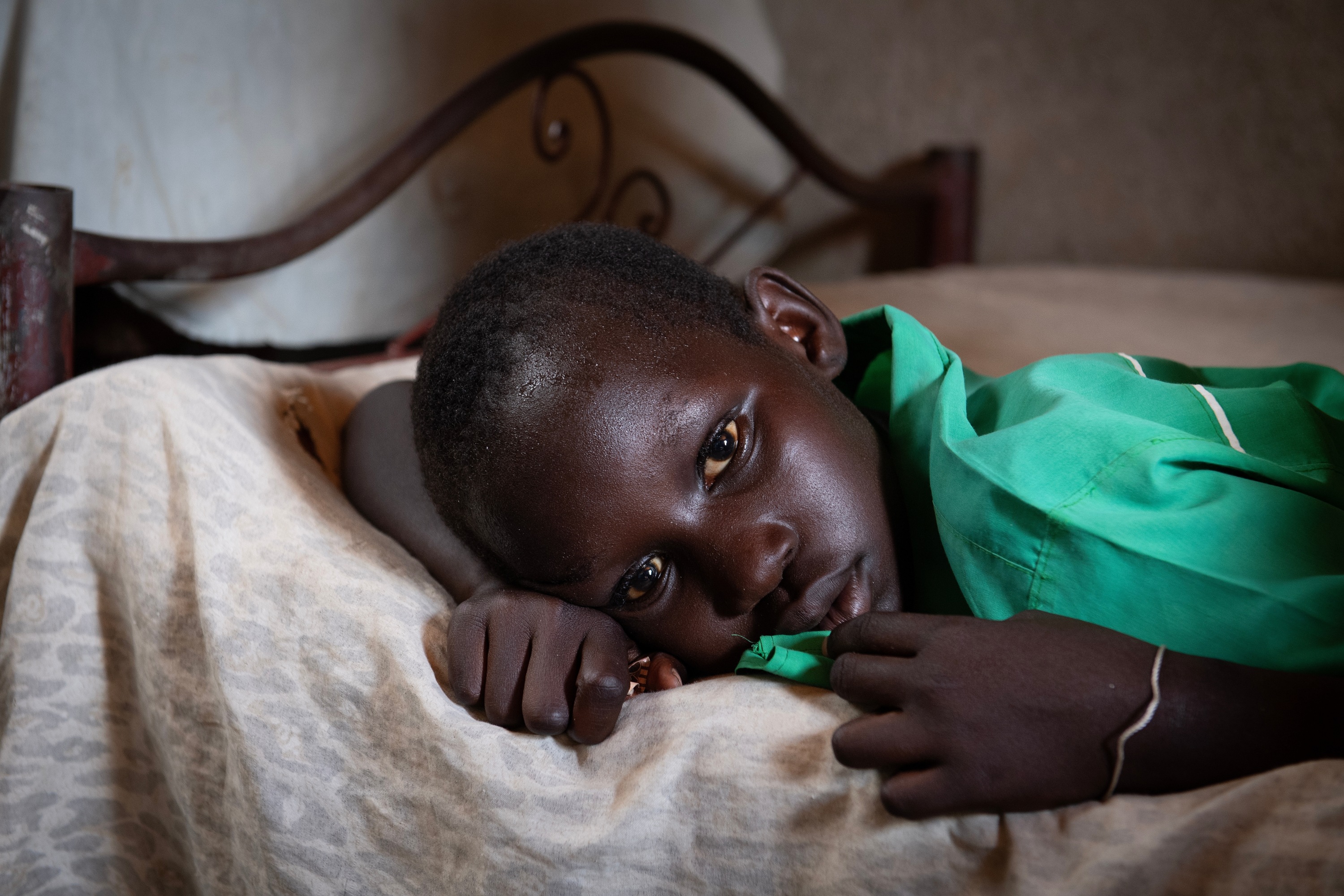 A child lies in bed suffering from malaria