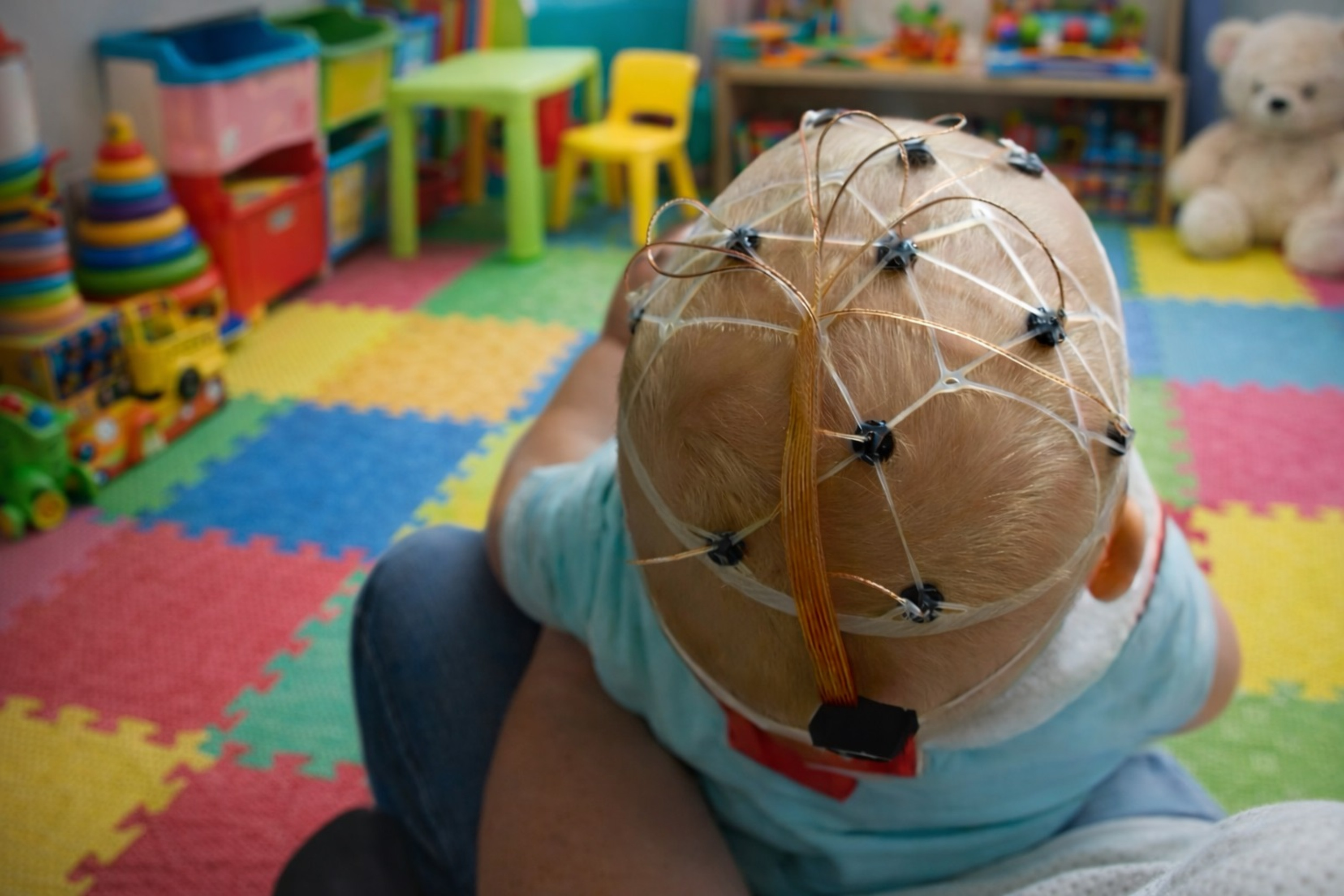A baby wearing an EEG cap shot from behind