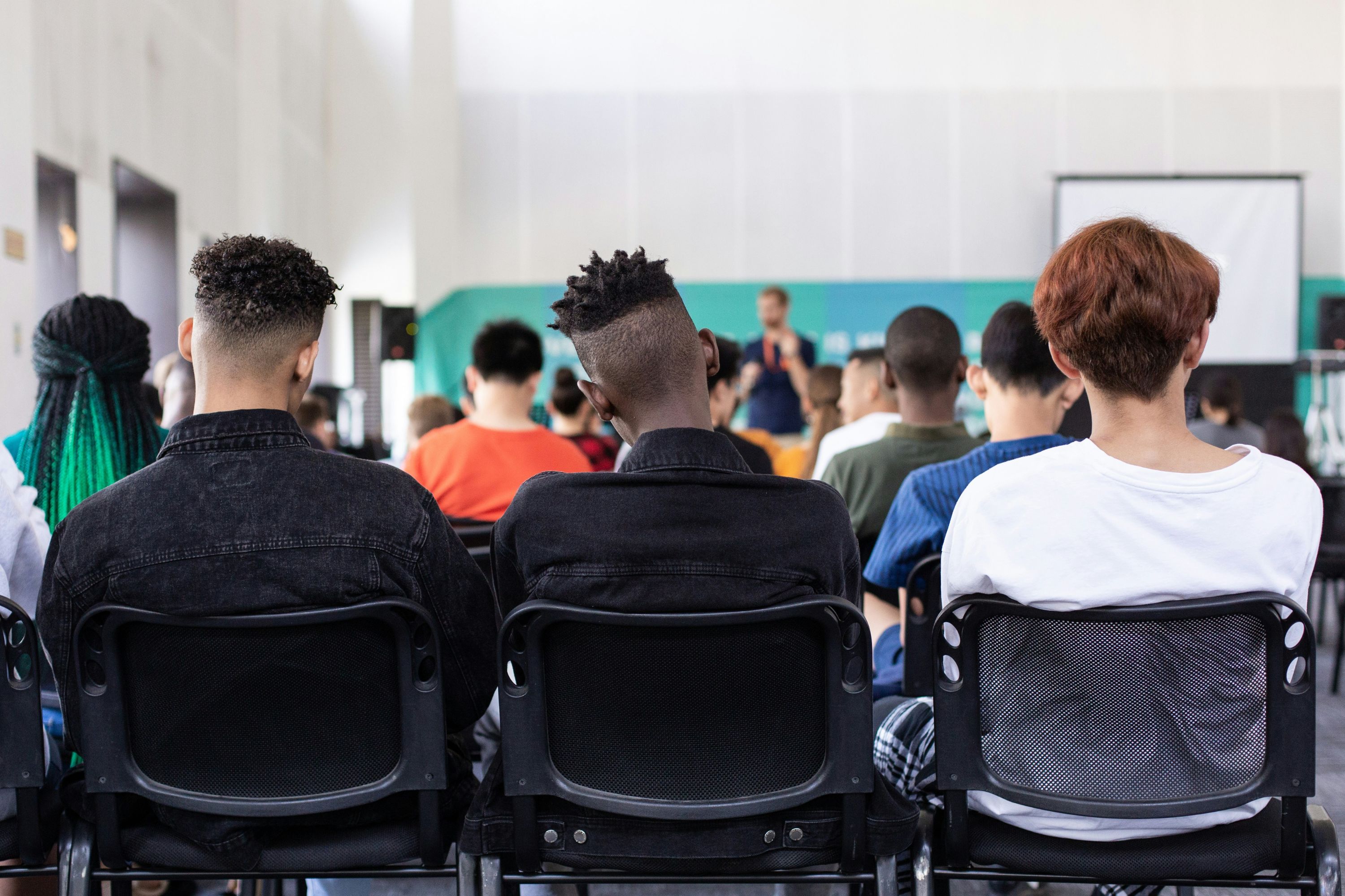 Three male students sitting at the back of a classroom