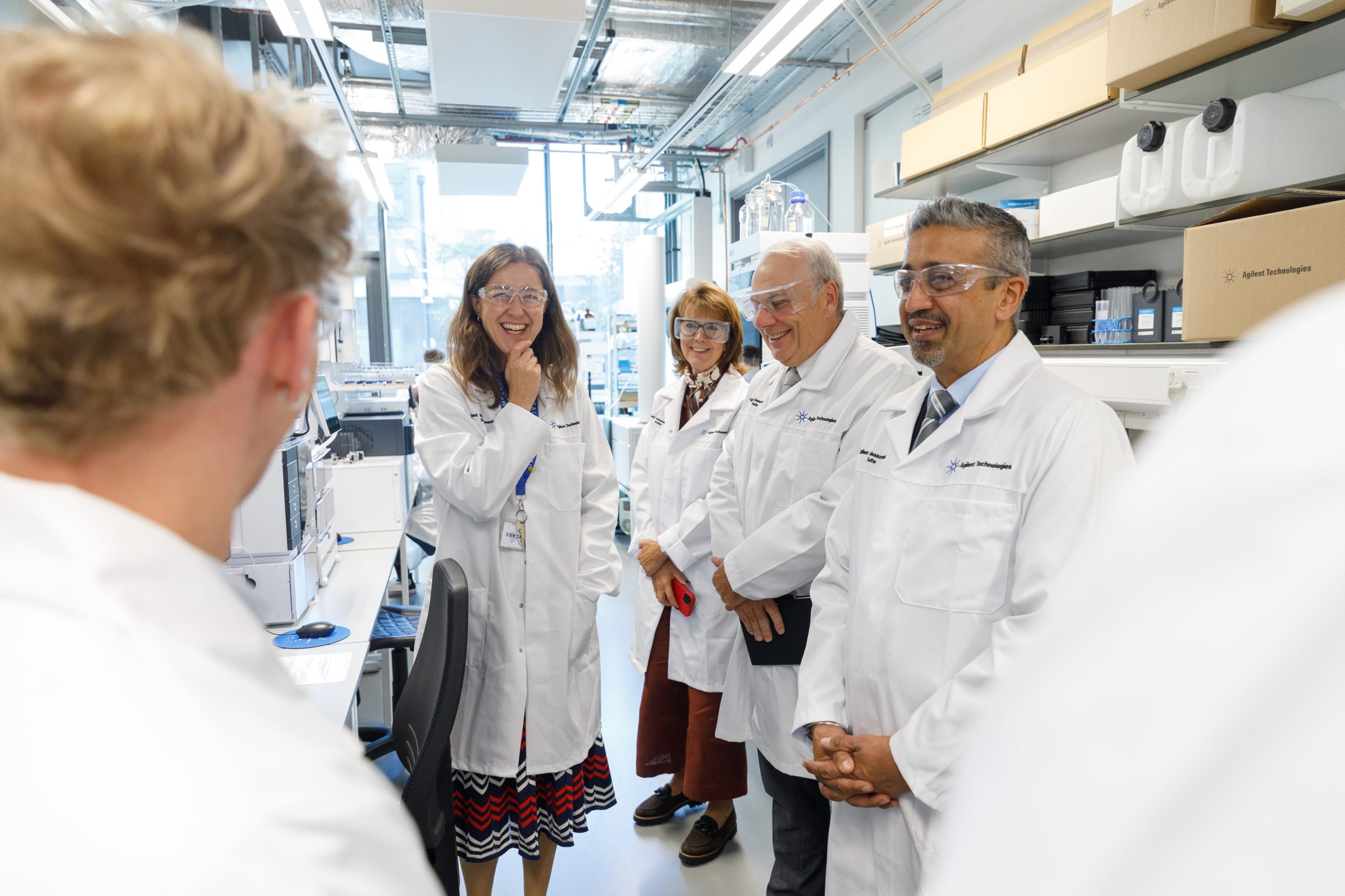 a group of people in white coats stand in a lab