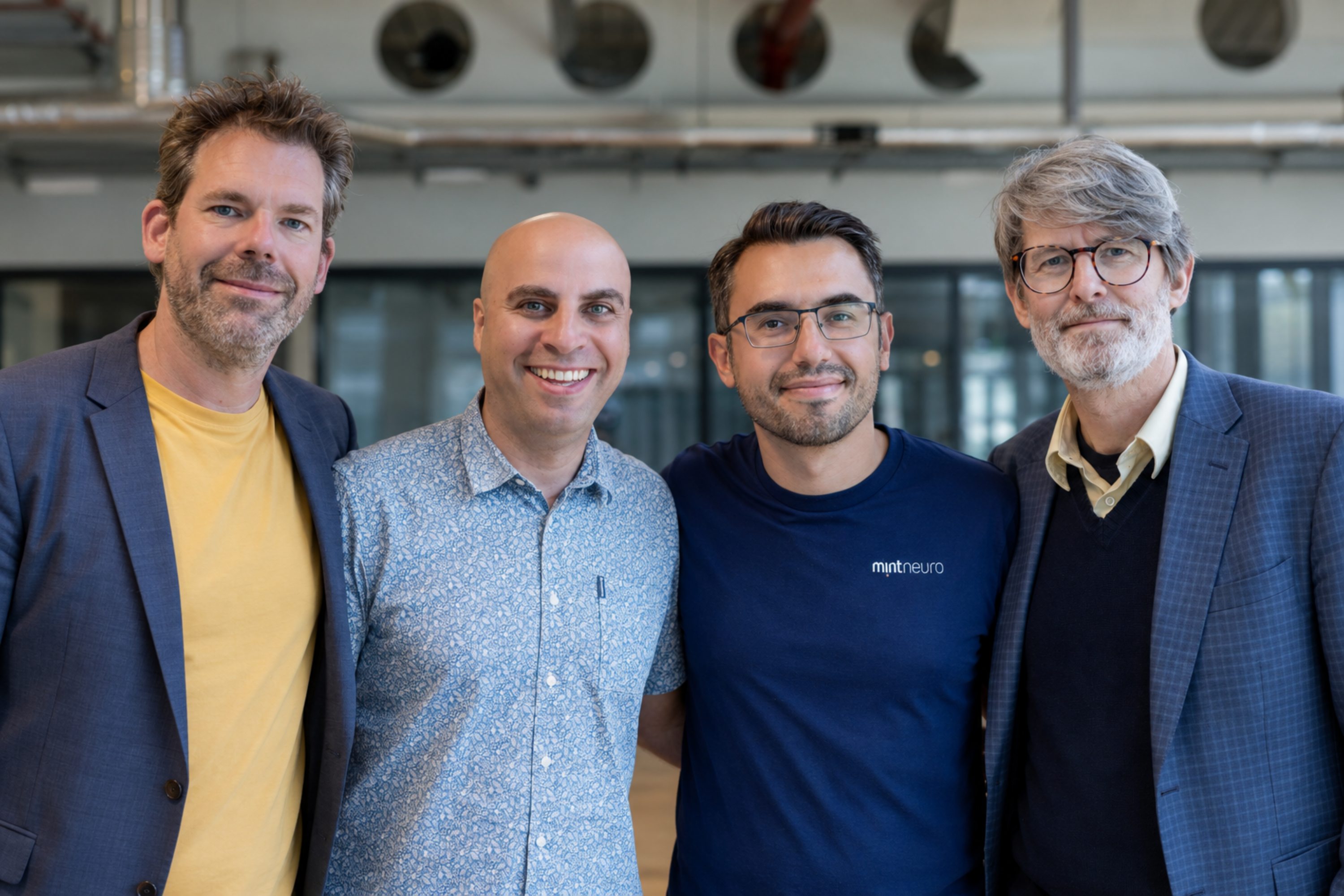 Four smiling men stand in a group