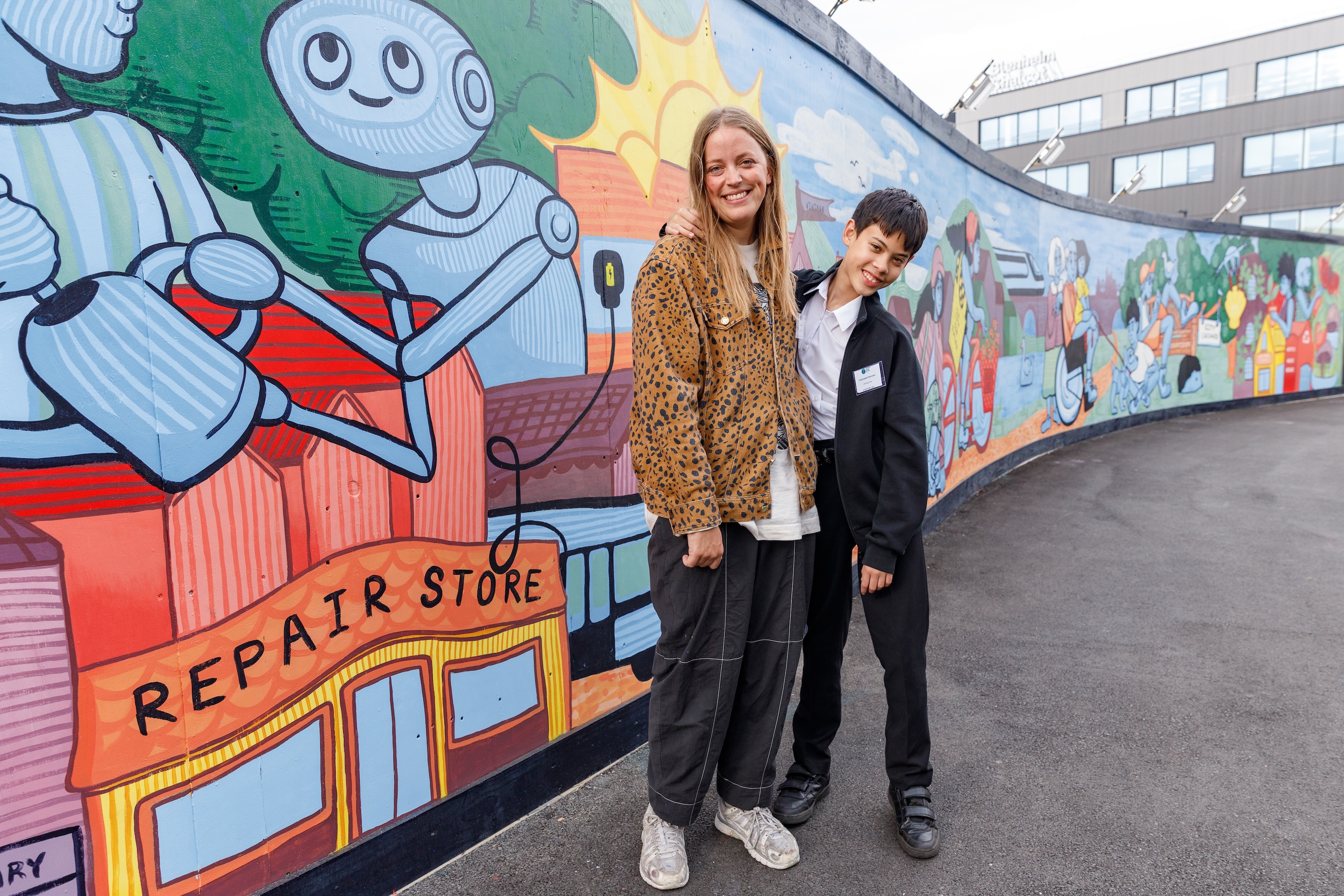 Painted mural depicting green urban cityscape, in White City with artist Jeru Nomi and competition winner  Christopher Simmons