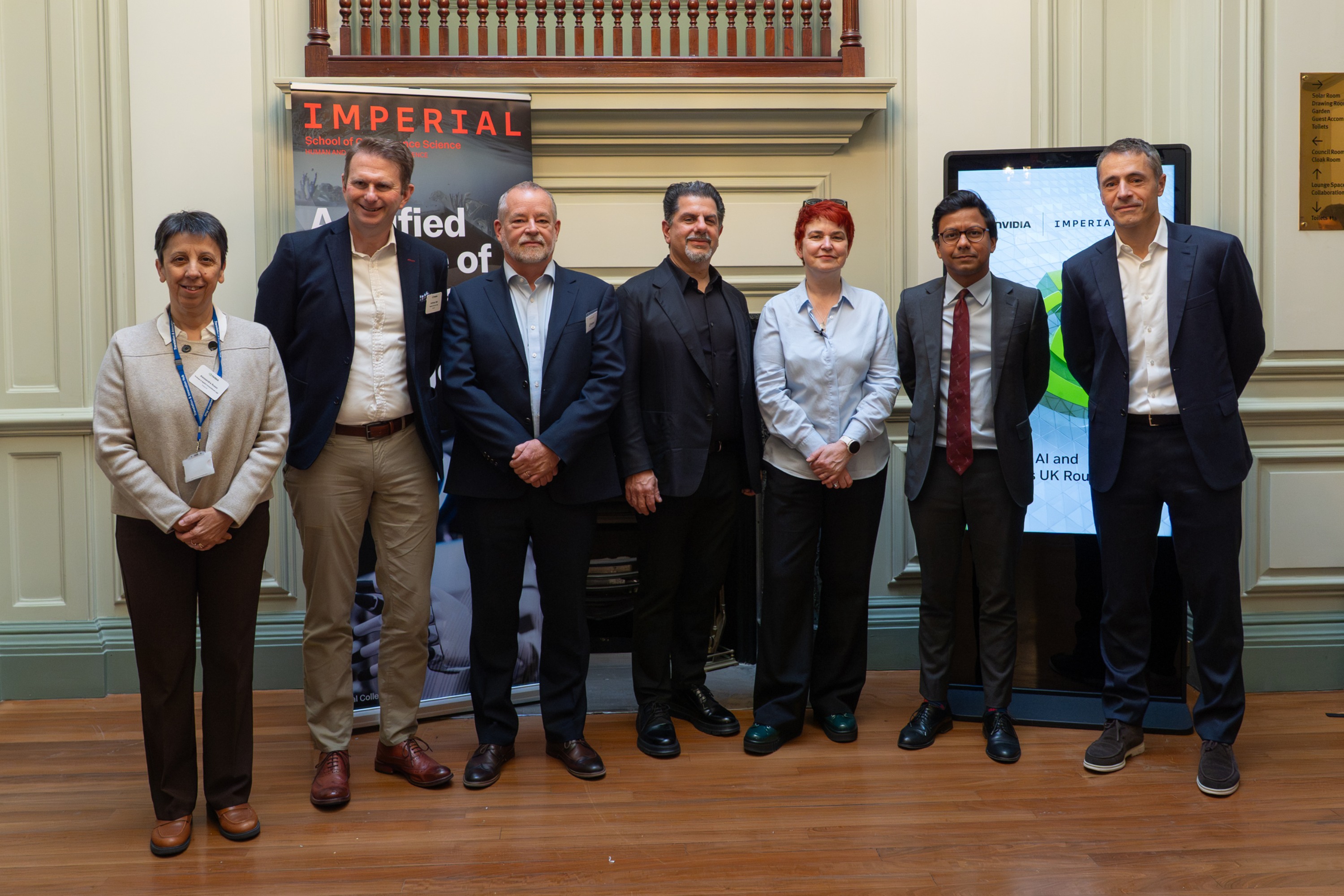 A group photo of 7 key participants lined up in front of Imperial and NVIDIA event signage - including Professor Alessandra Russo and Professor Mary Ryan from the Imperial side
