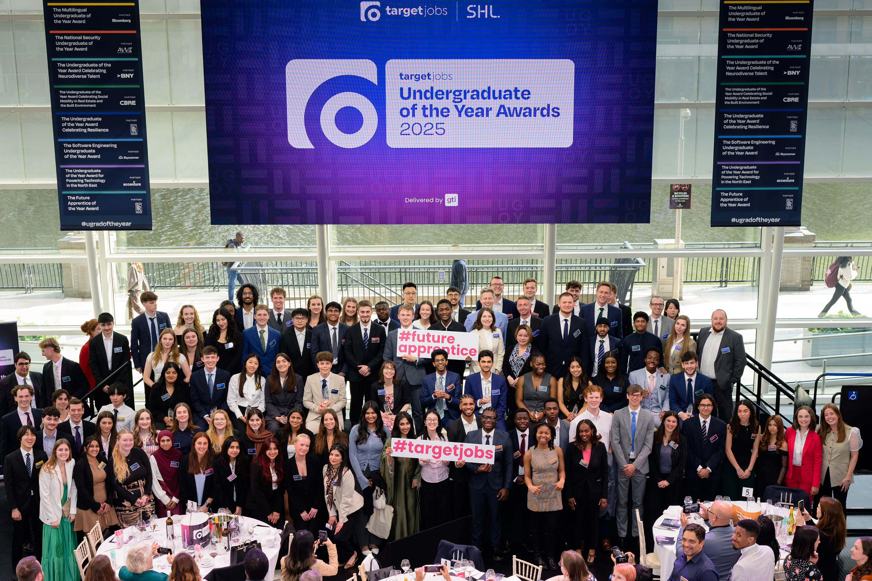 picture of the finalists of last year's event with their employer sponsors, holding signs reading '#FutureApprentice' 'UGOTY25' and '#TargetJobs'