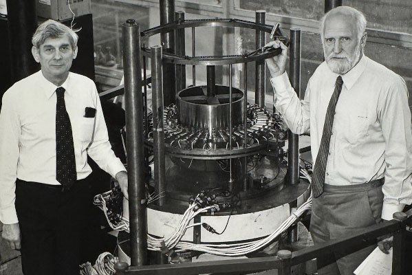 Jack Neale standing by equipment in the structures lab with colleague