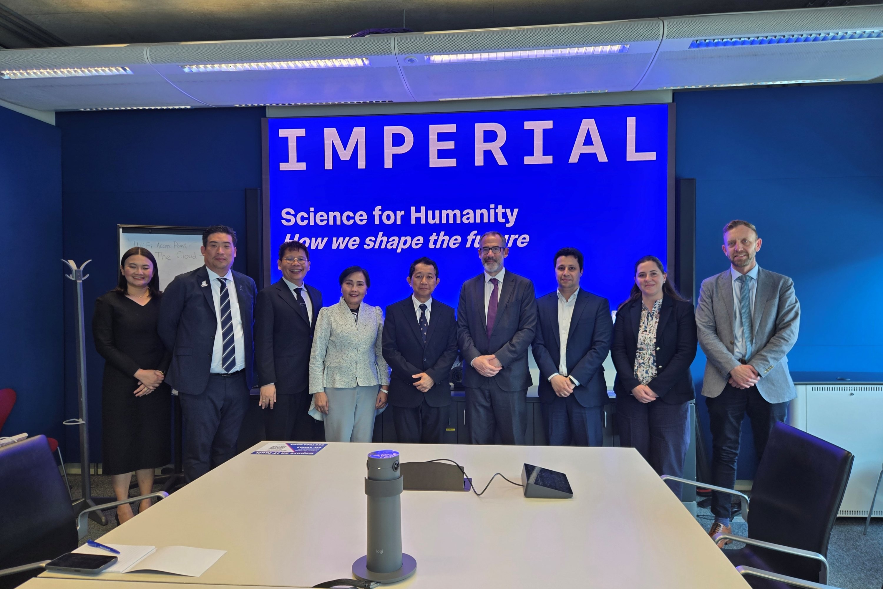 a group of delegates from TSRI, MUT and Imperial standing in front of at Imperial presentation