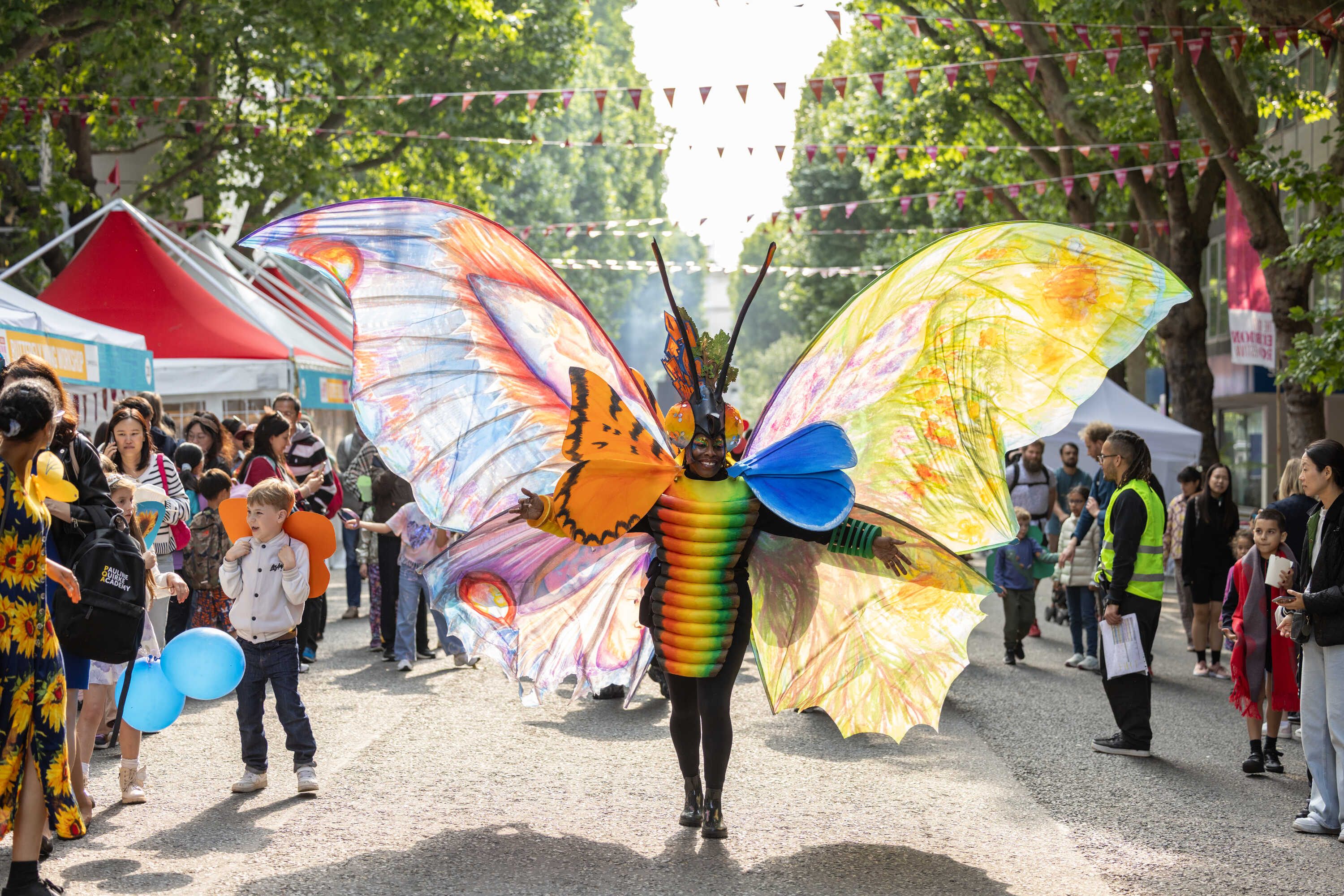 A person wearing giant multi-coloured butterfly wings parading down the Exhibition road at the 2025 Great Exhibition Road Festival 2025.