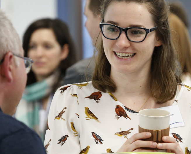 Man and woman talk whilst examining a reusable coffee cup