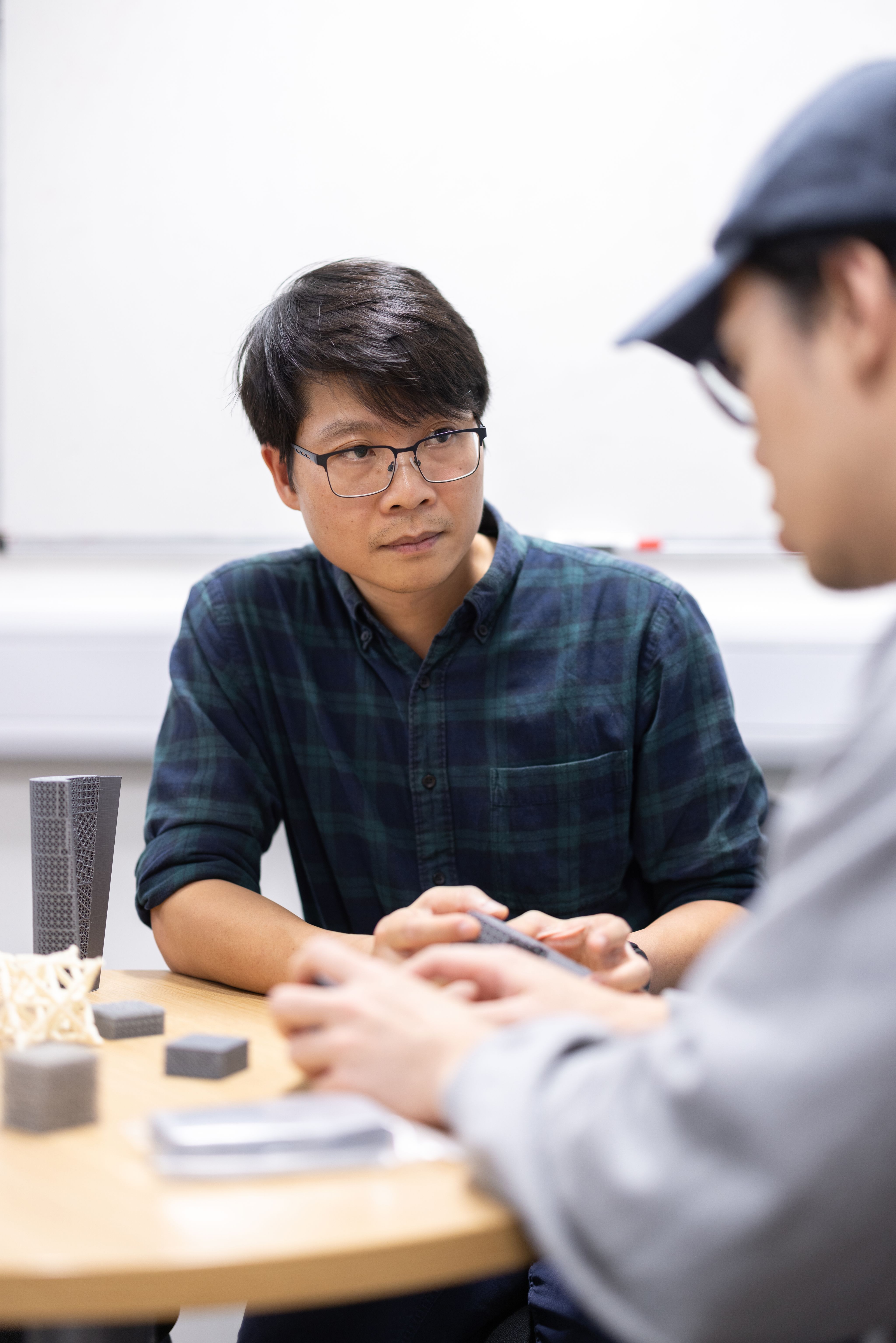 Dr Minh-Son Pham holding a 3D model while discussing this with his PhD student.