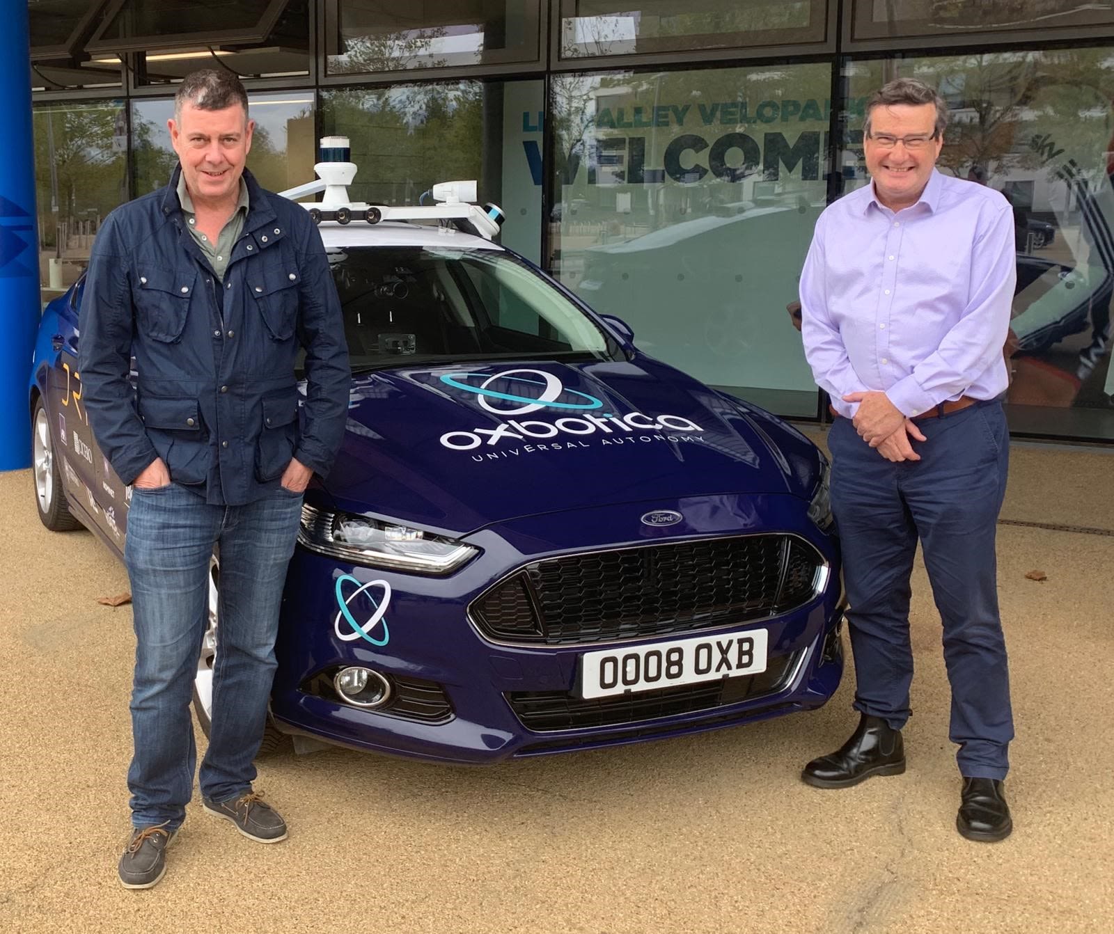 Parkwalk Advisors co-founders Alastair Kilgour and Moray Wright stand infront of a car which says Oxbotica on it, one of their investements
