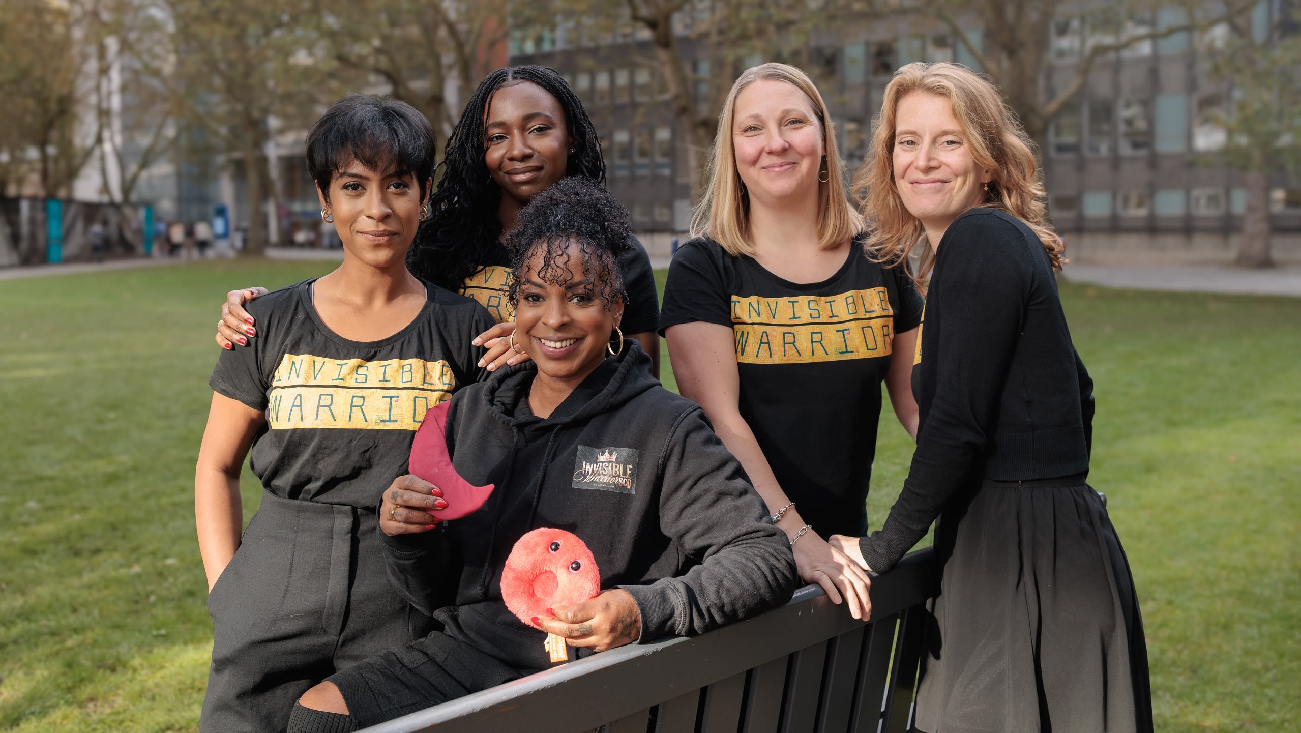 Team members of the Invisible Warrior Project, five women positioned close together, smiling, outdoors.