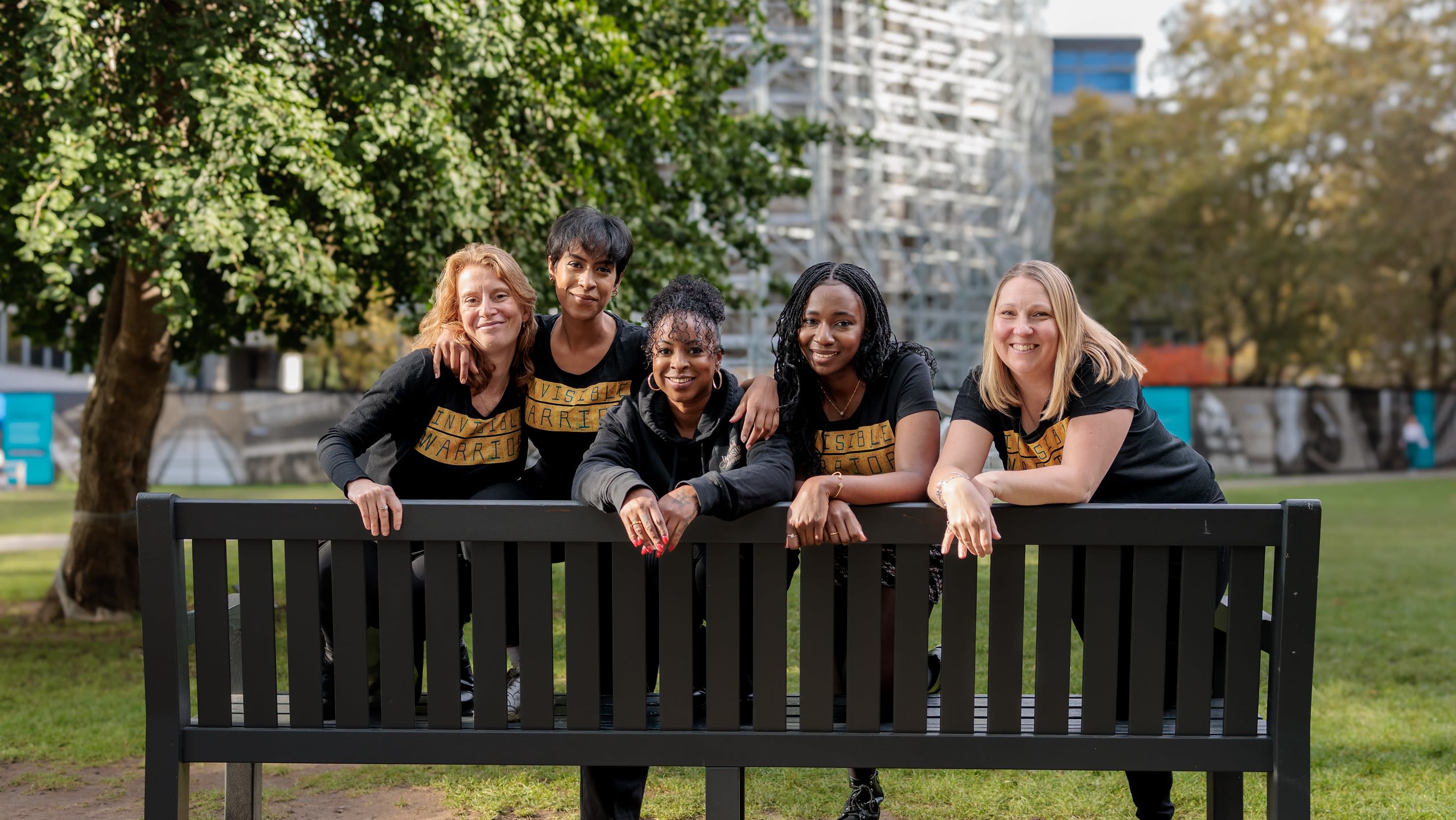 Five women posing on a bench.