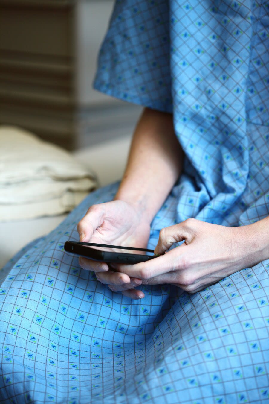 a person in a hospital gown holding a phone