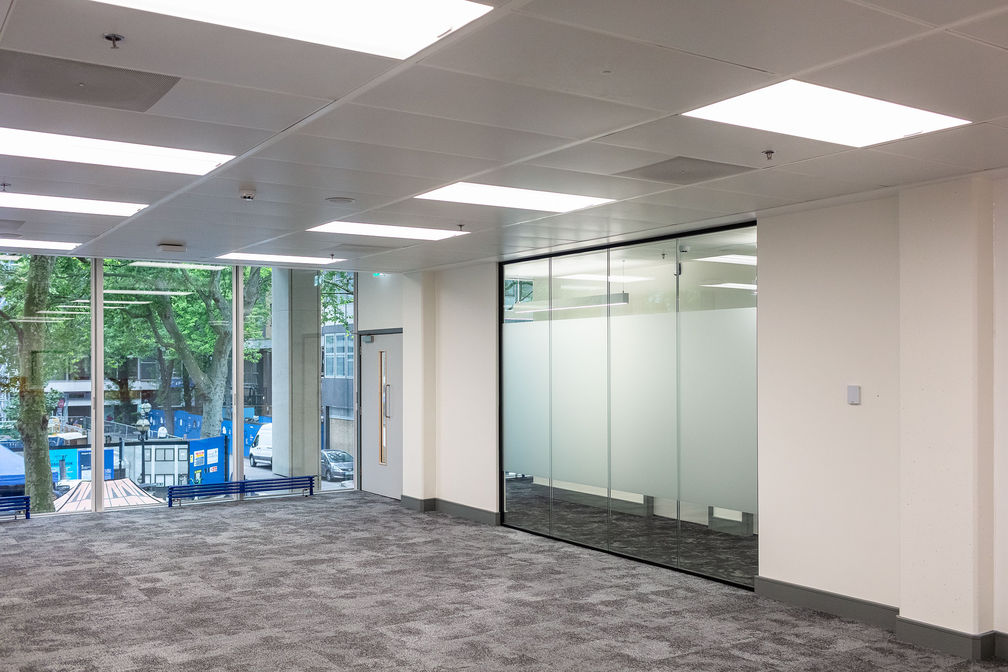 An empty office with a large picture window, glass wall on one side and door