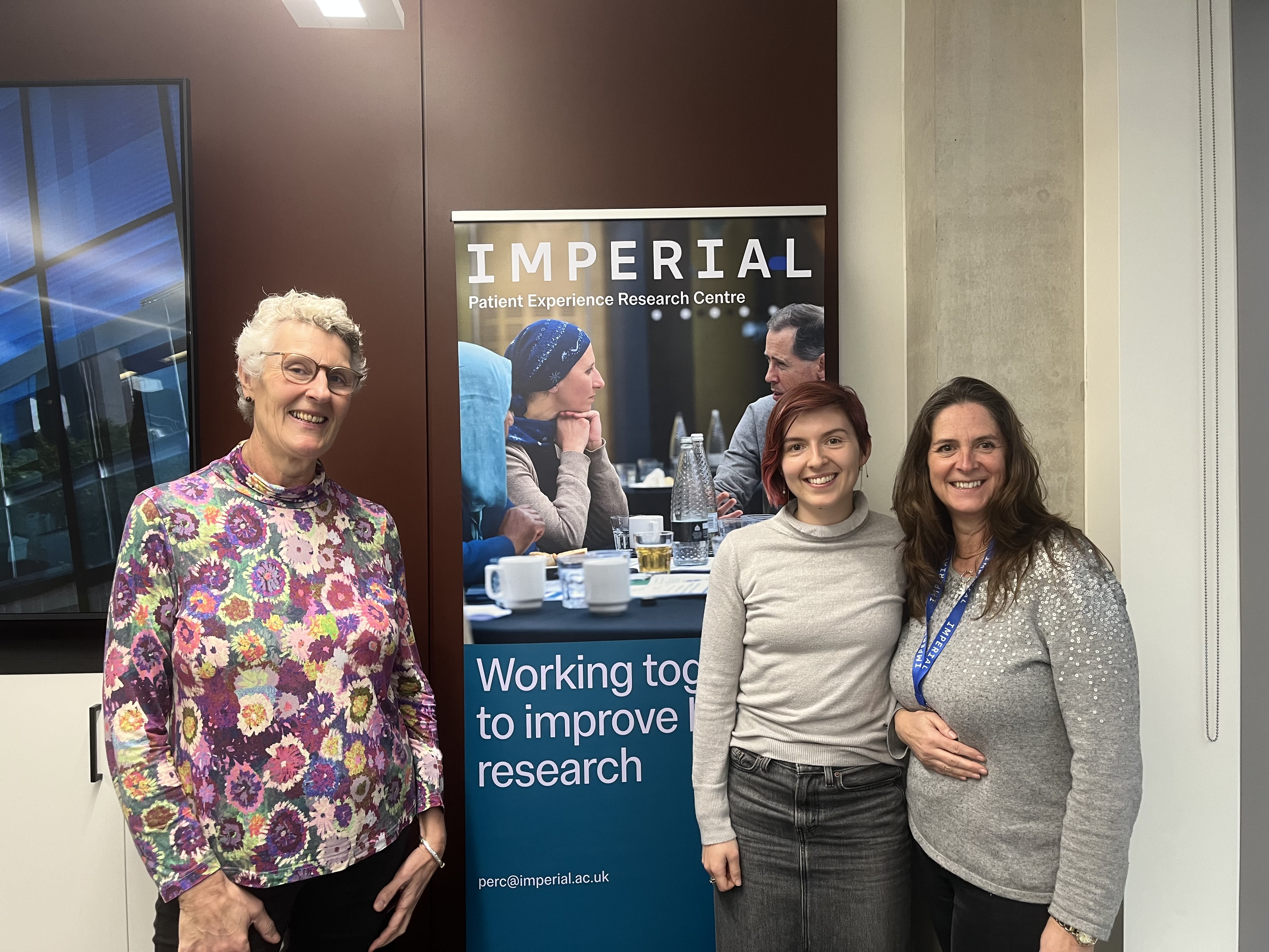 Dr Kathryn Jones, Carmen and Annie smiling in front of a banner