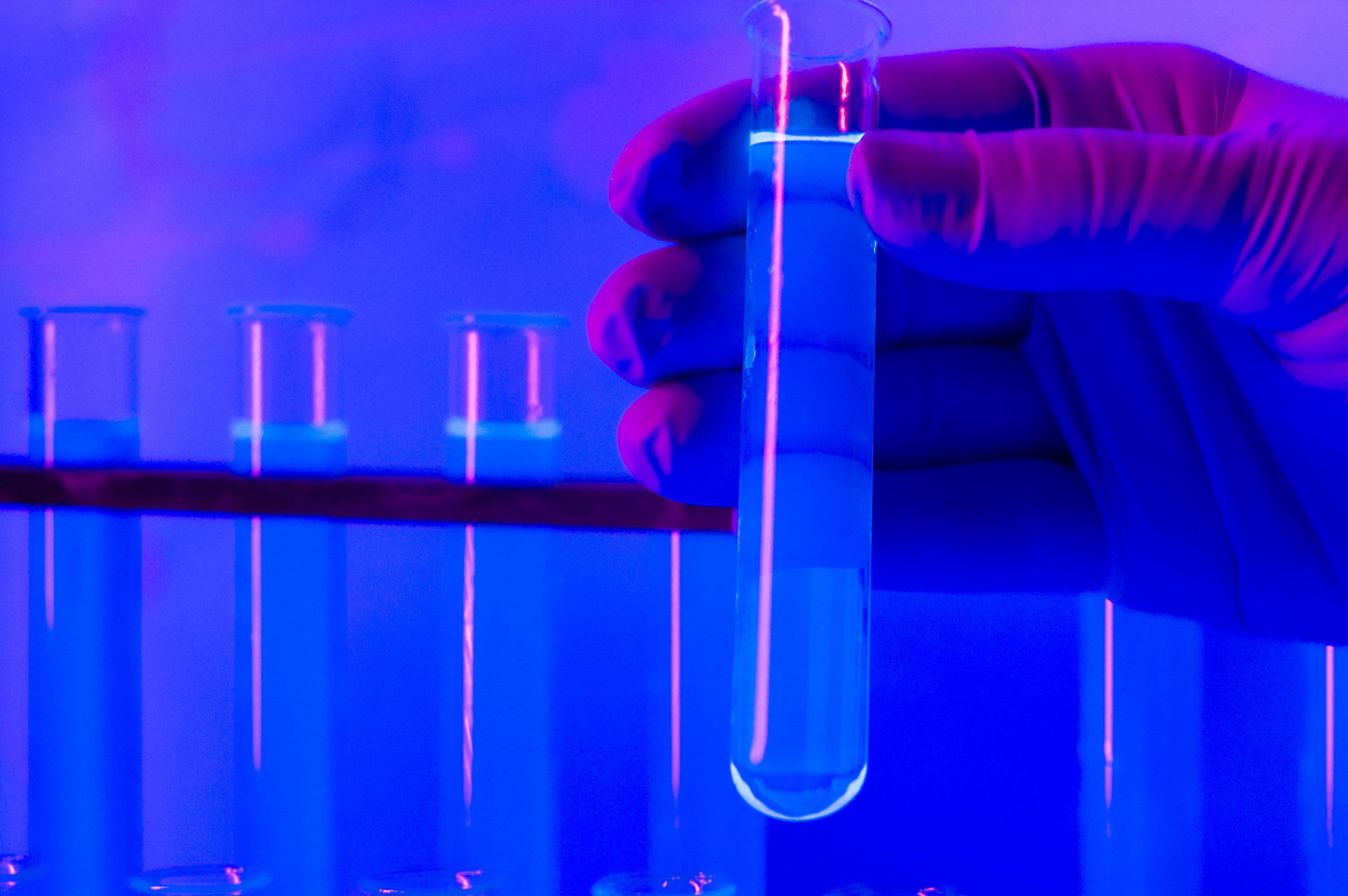 Gloved hand holding a text tube containing a liquid sample