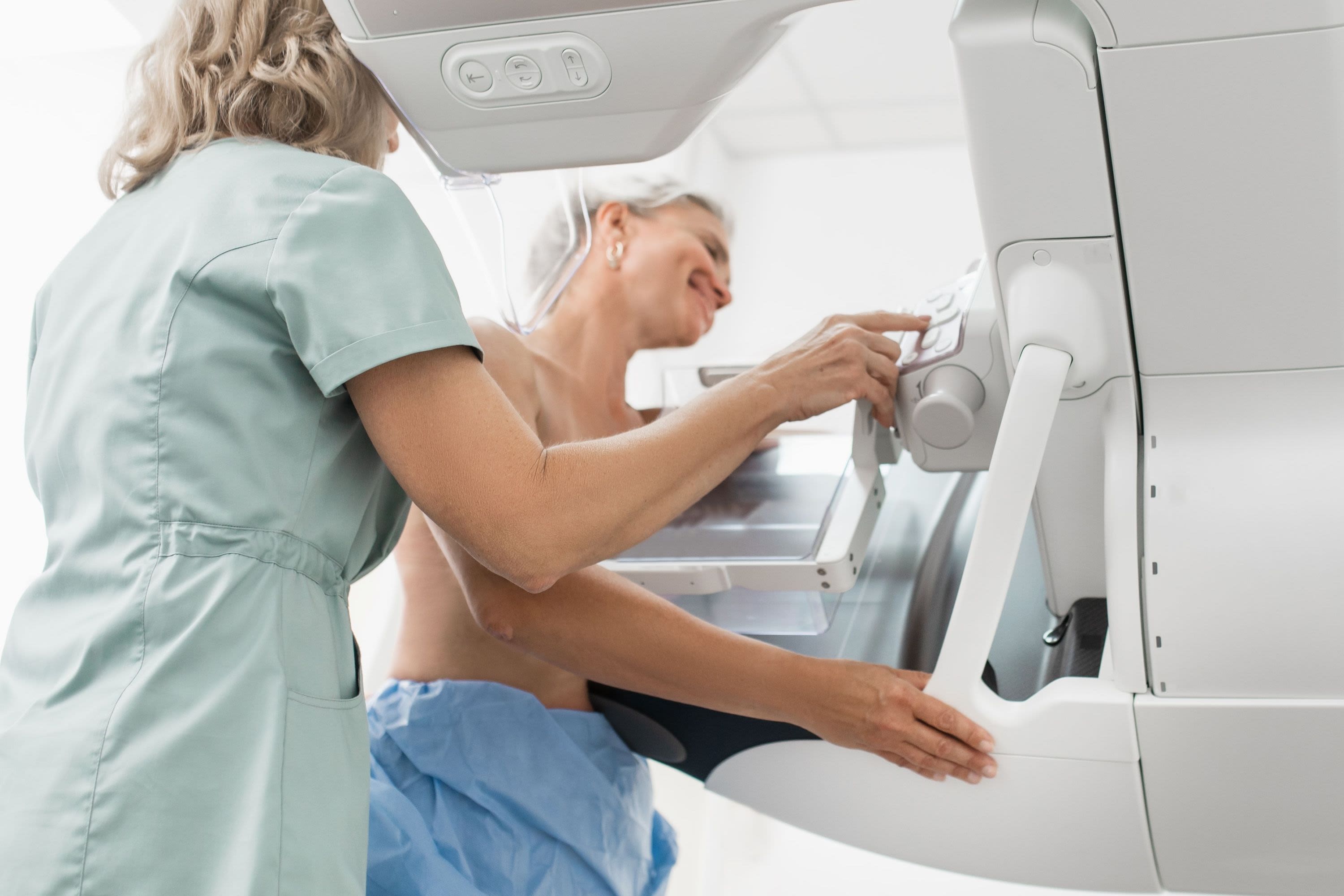 A woman having a breast cancer scan, aided by a healthcare professional
