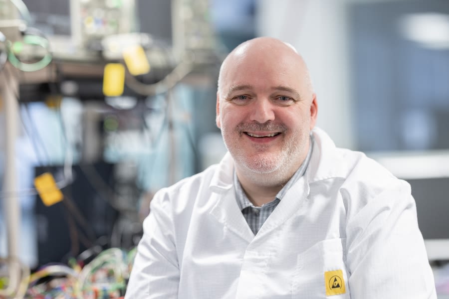 A man wearing a white coat smiles at the camera