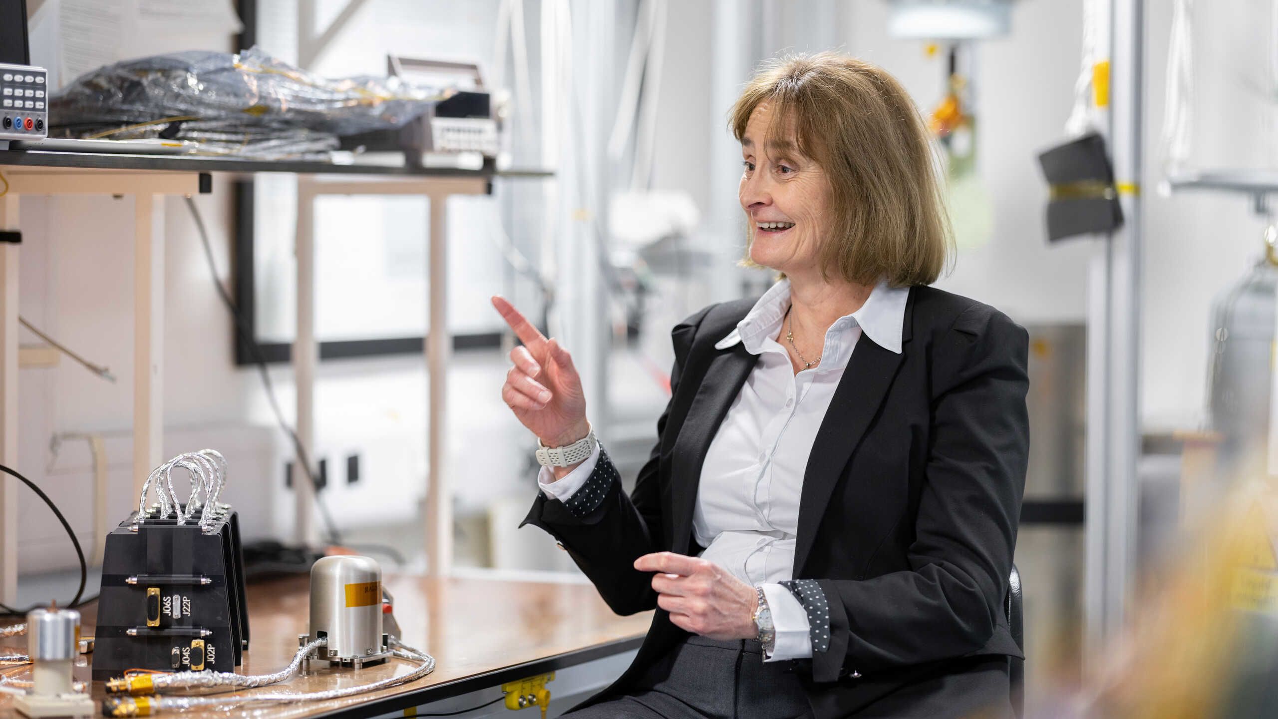 Professor Michele Dougherty laughs and points to the side in a lab