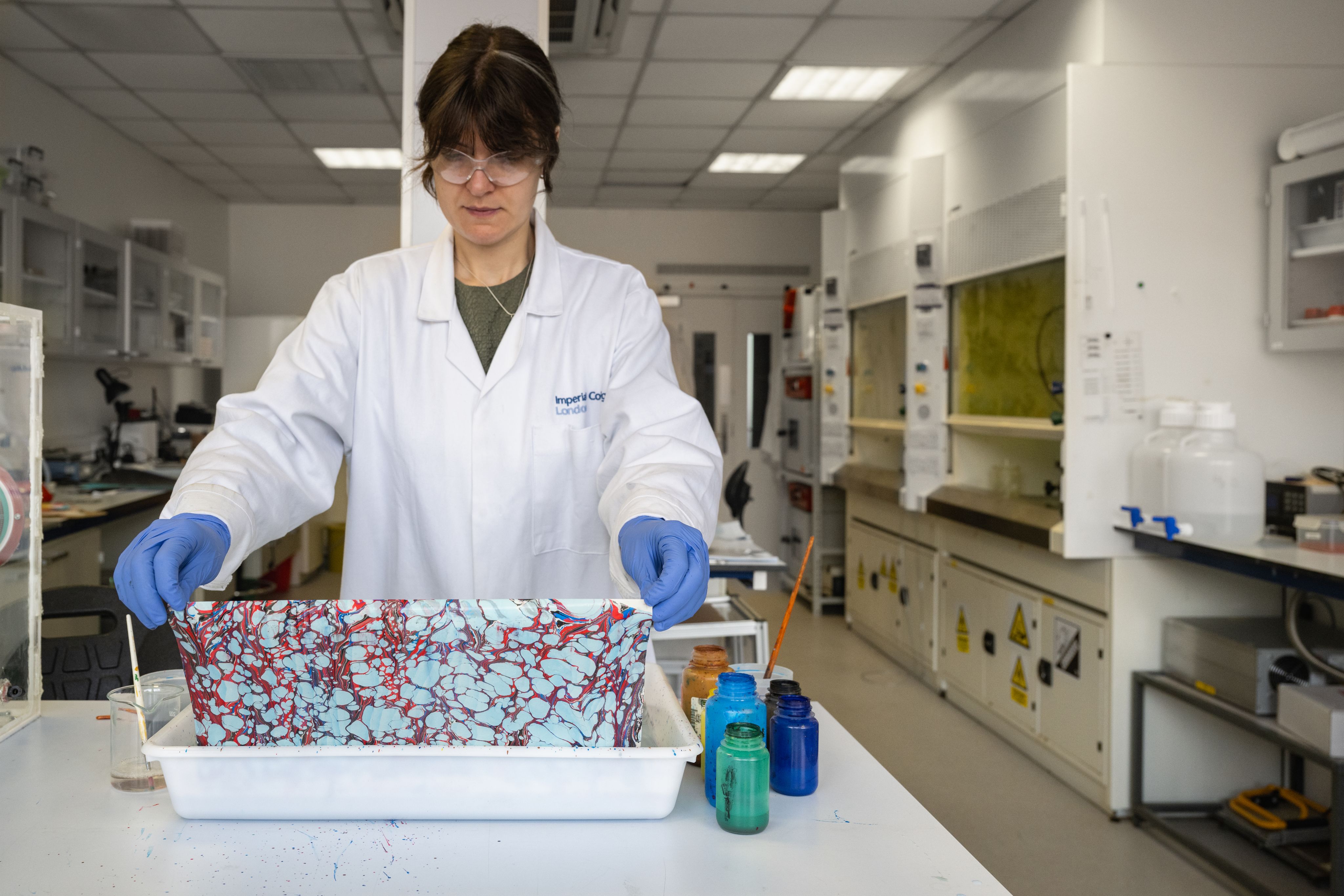 Liva carefully pulling a completed print out of the marbling container in the laboratory.