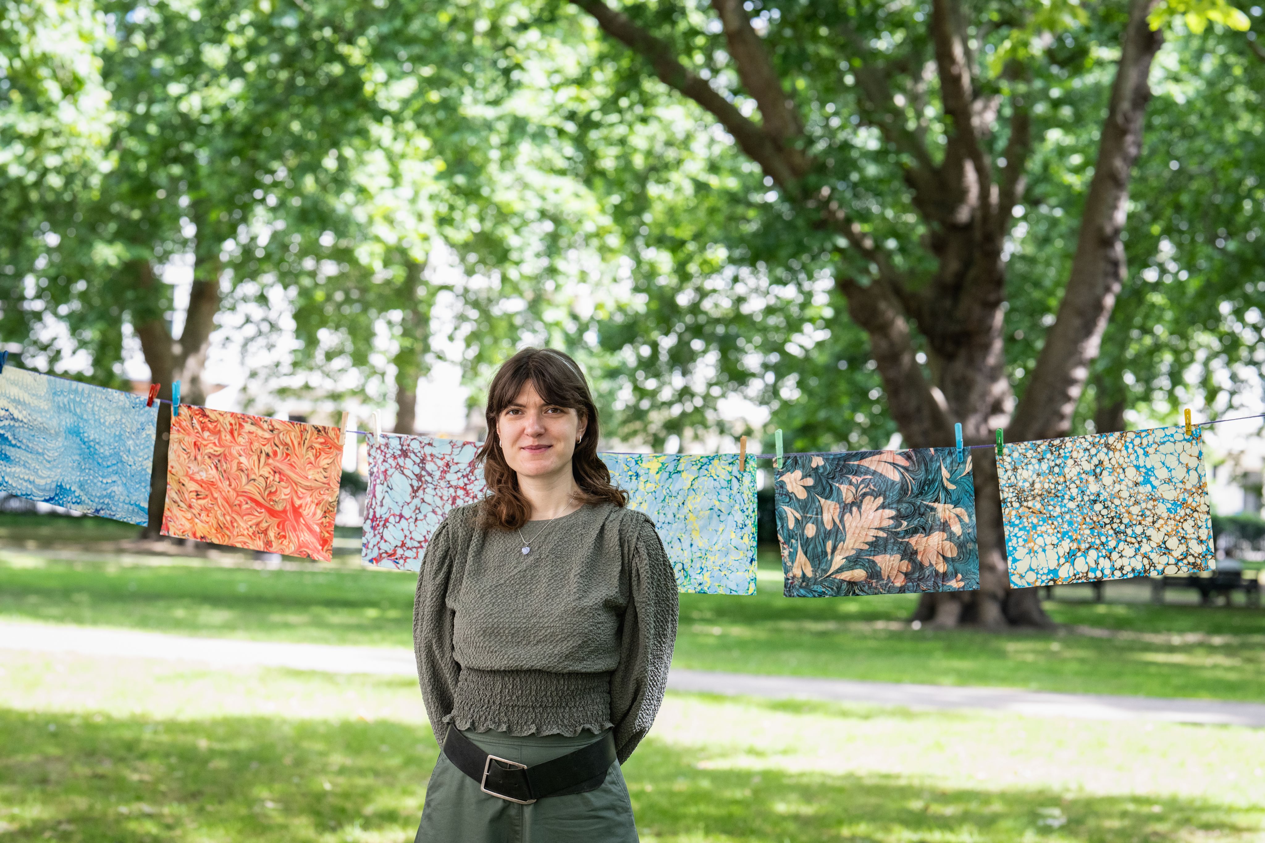 Liva standing in front of a row of marbling prints displayed behind her.