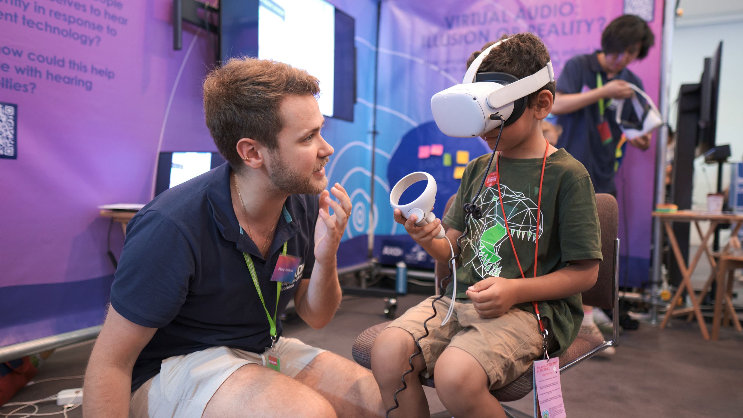 A child with a virtual head set on and a man helping him handle the controls