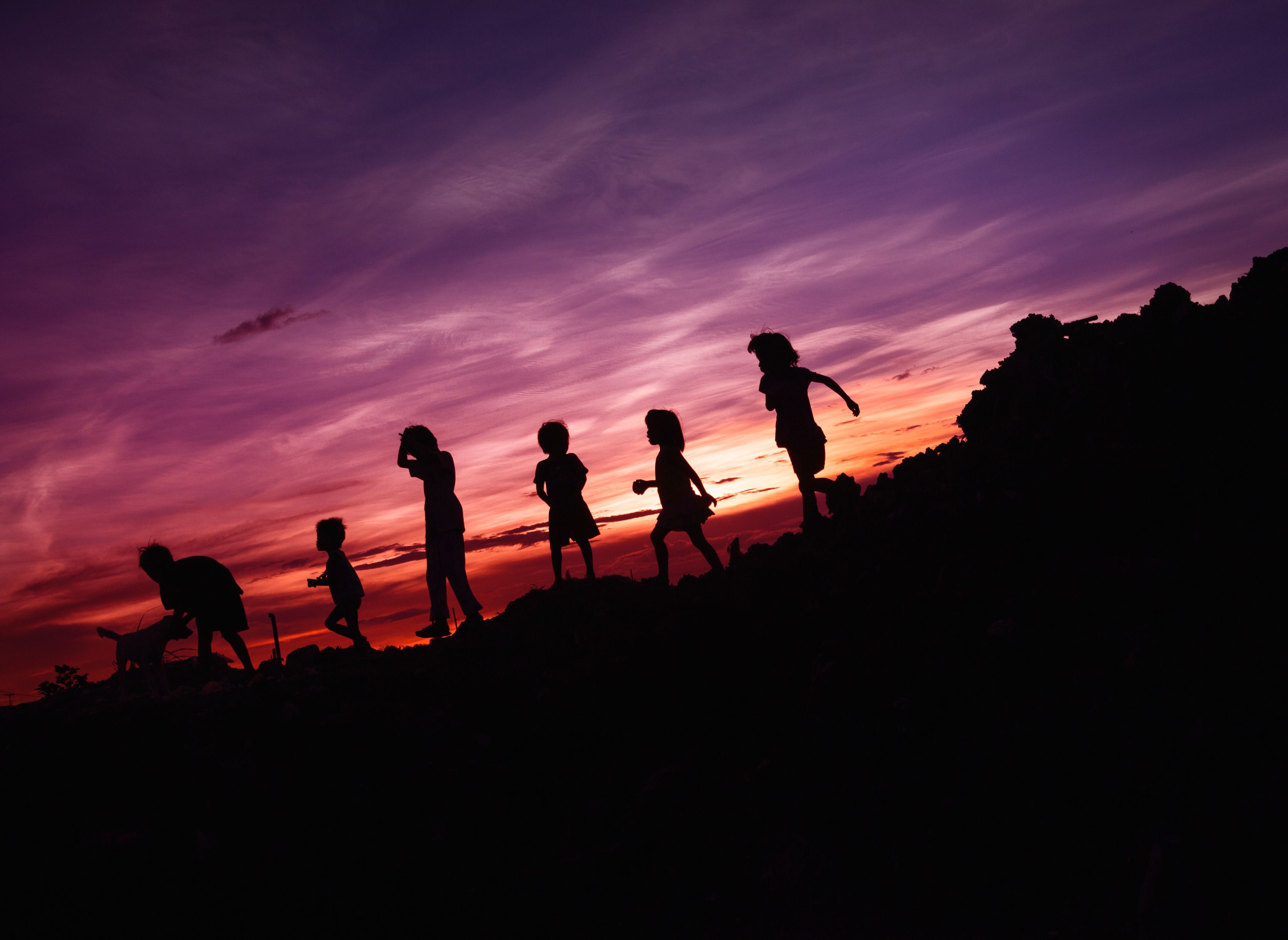 Children run along wall at sunset