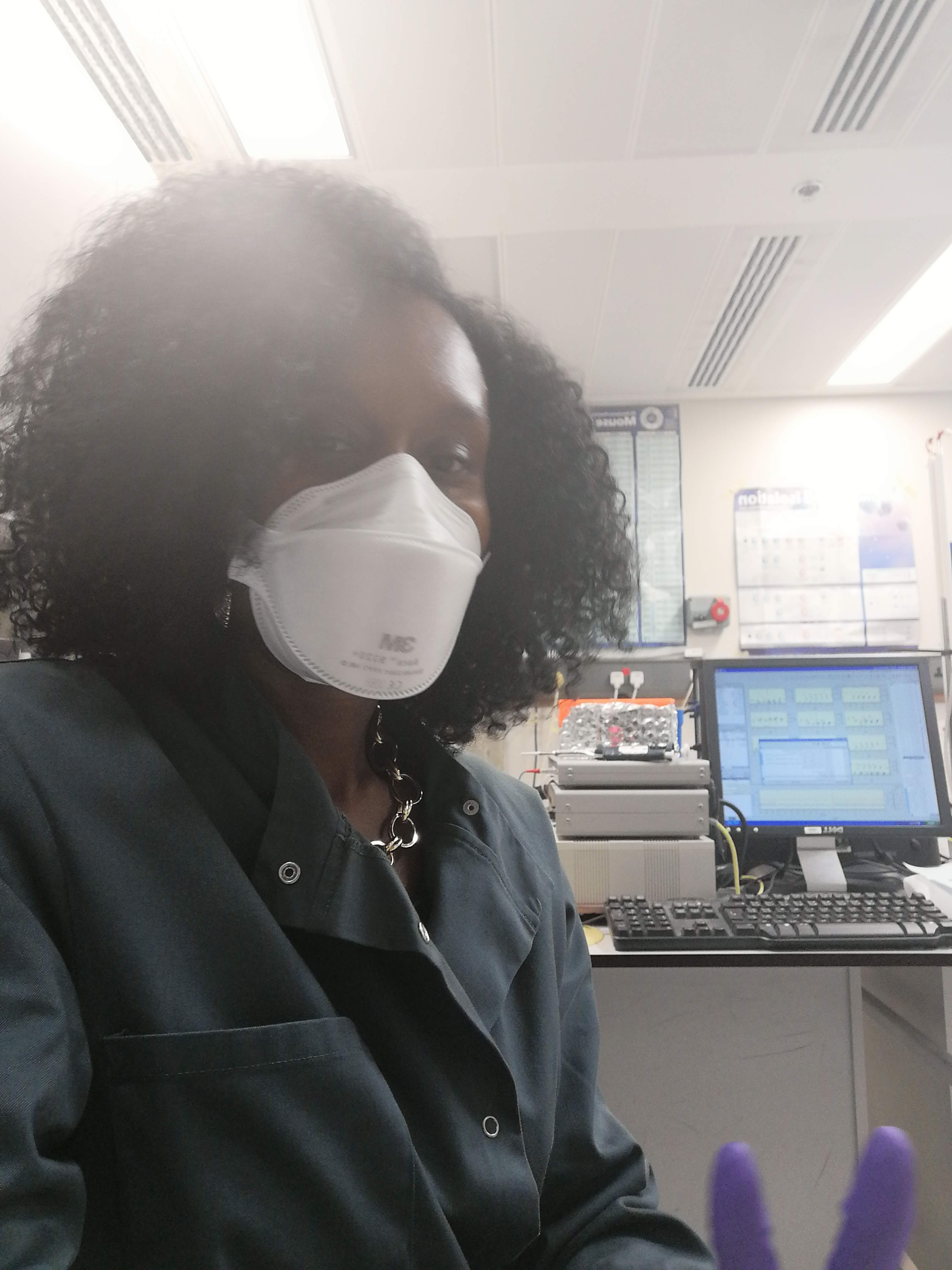 Simone with face mask in front of computer