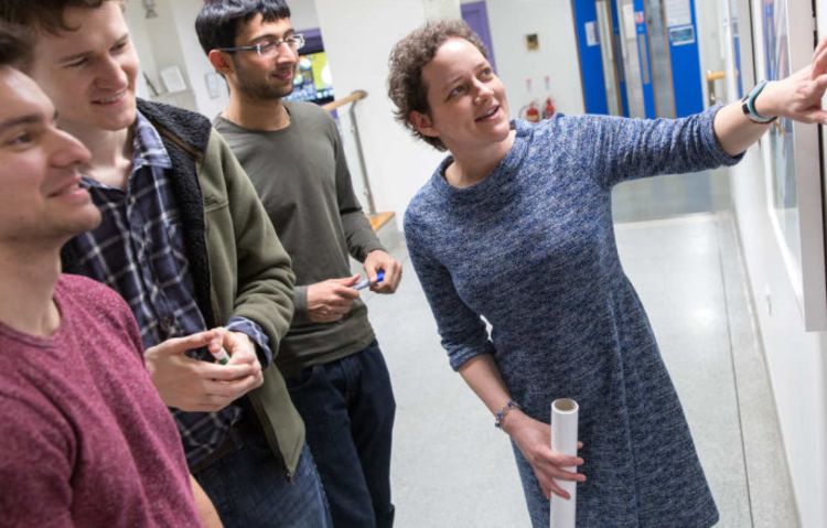 Students looking at a whiteboard in a classroom.