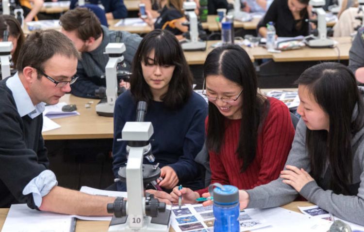 Students using a microscope in a classroom.