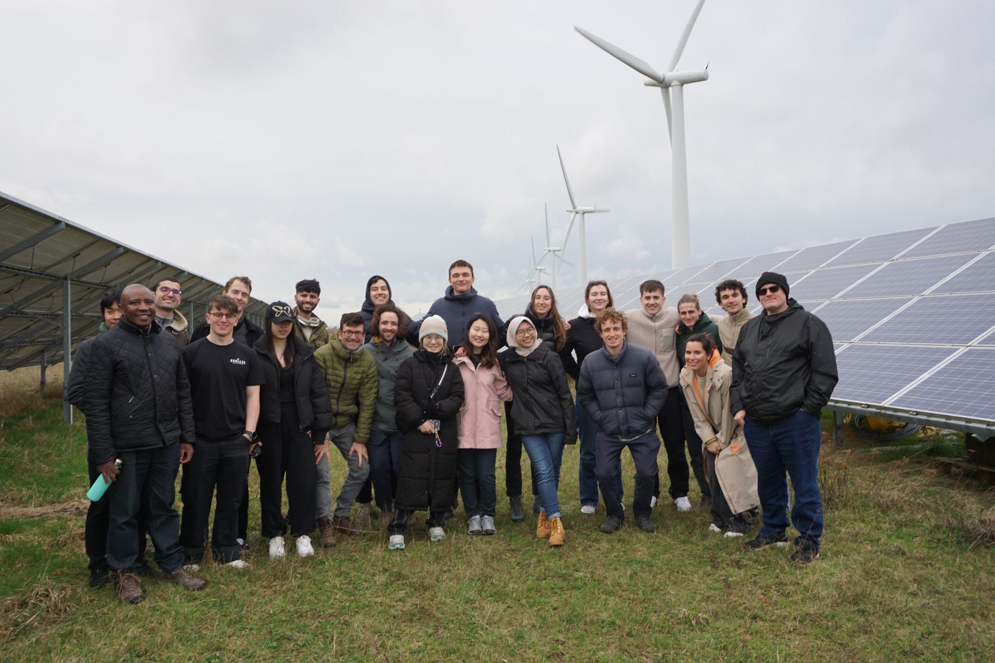 Group picture of Alexandra and other MSc Environmental Technology students standing outdoors, with solar panels and wind turbines in the background