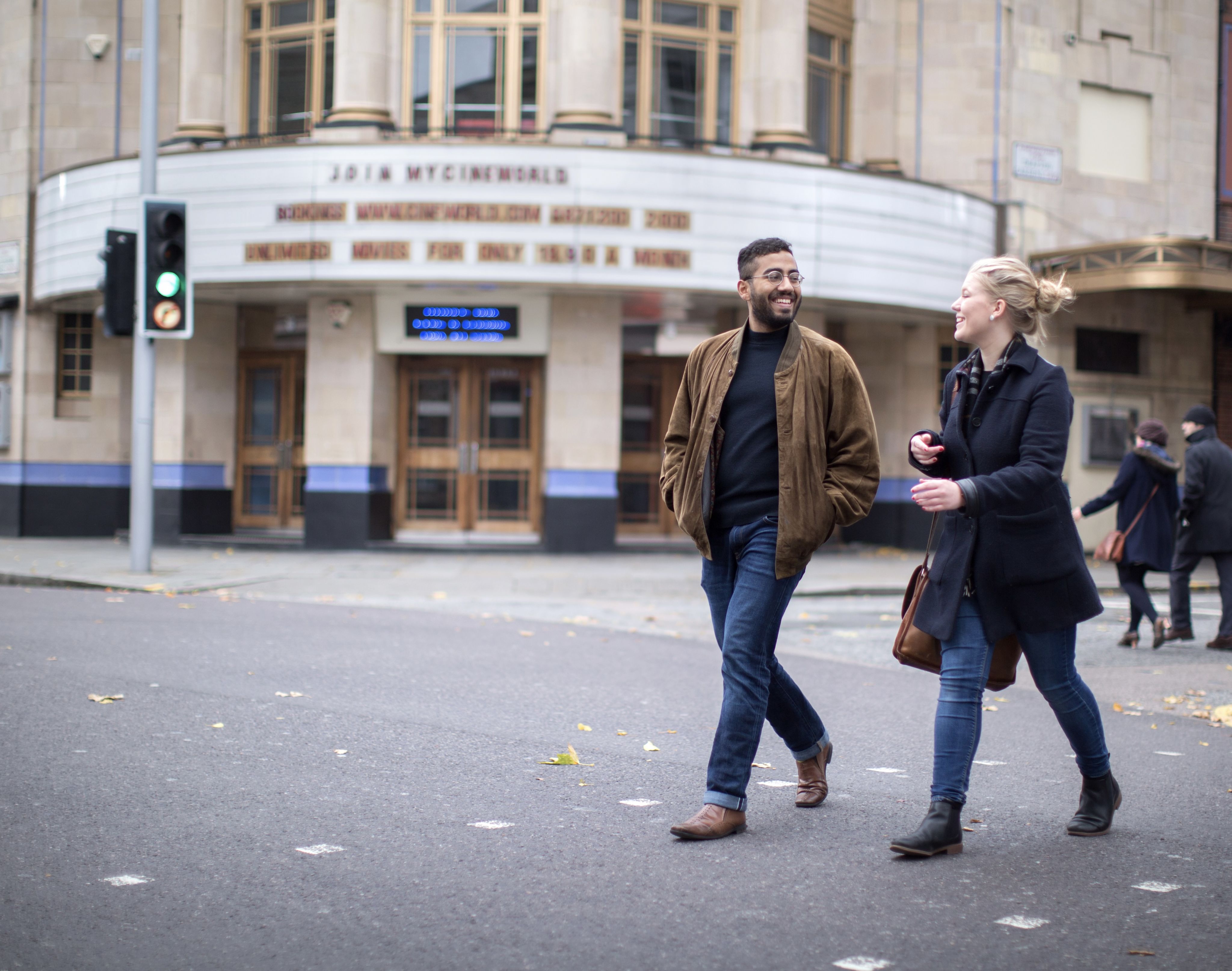 Two students walking on a street in London, with a theatre in the background