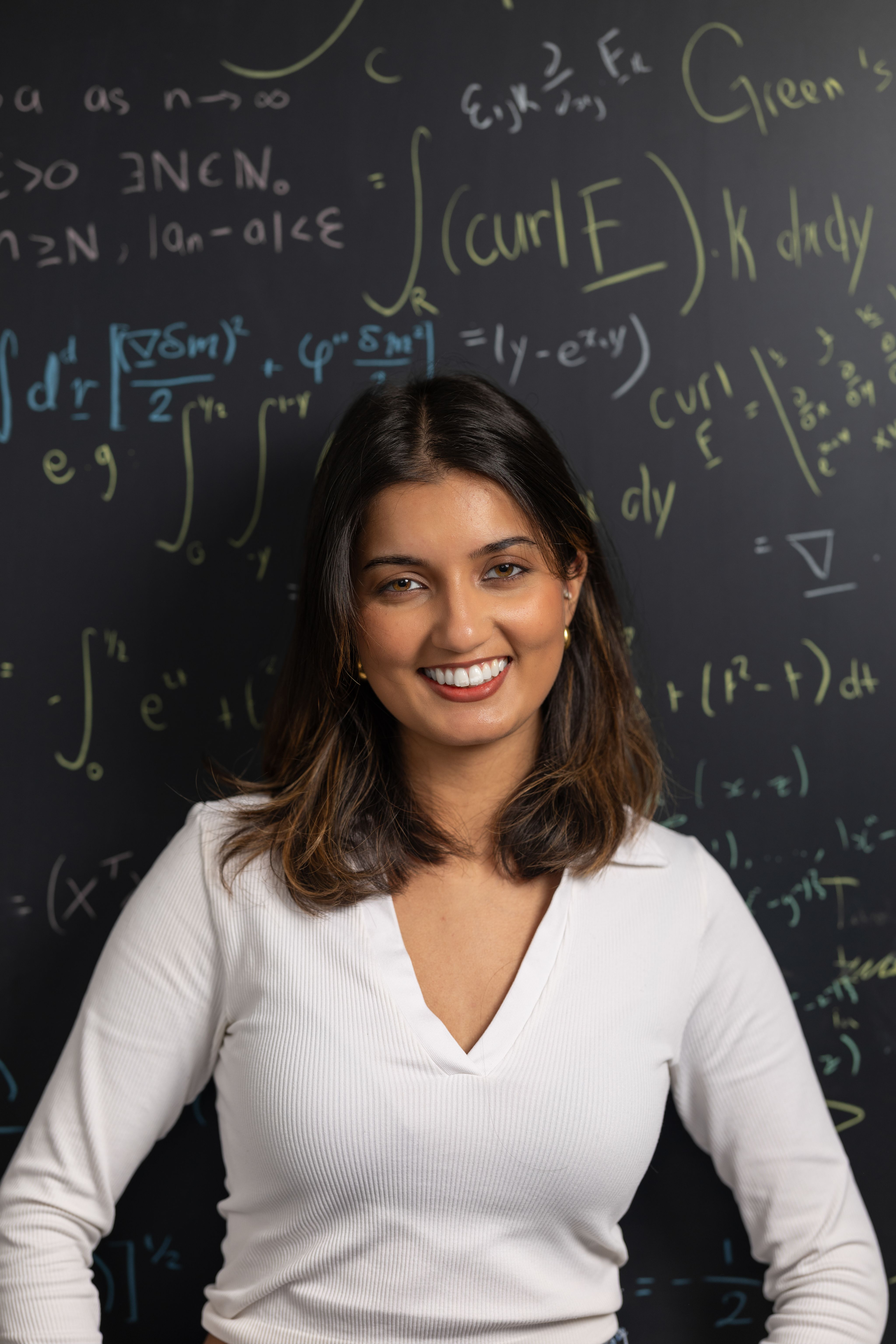 Alexia stood in front of a black chalkboard covered with maths equations.