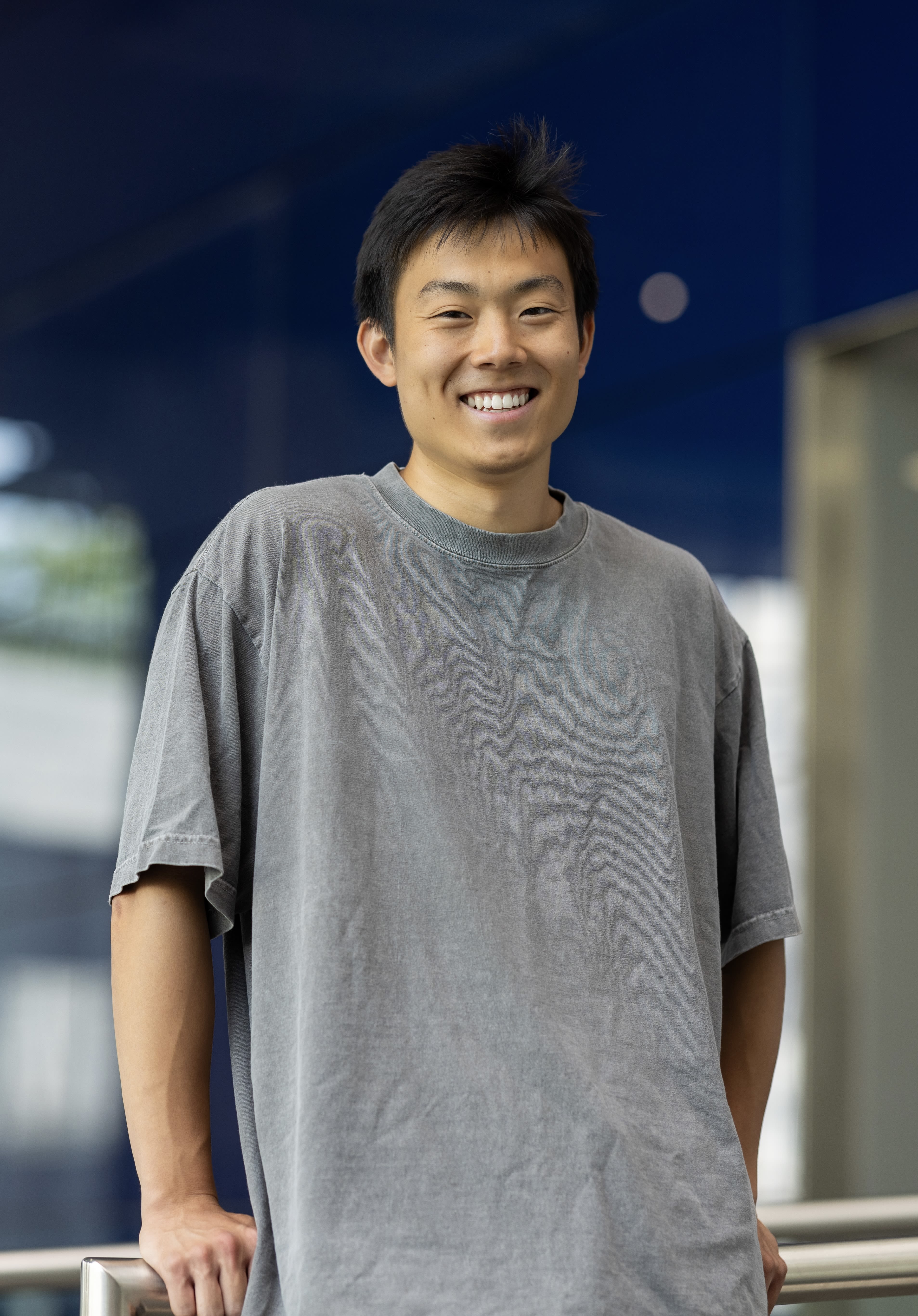 Andrew wearing a grey shirt, standing in the main entrance of South Kensington Campus