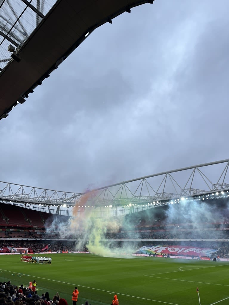 The Emirates Stadium football pitch with colourful smoke in the air  